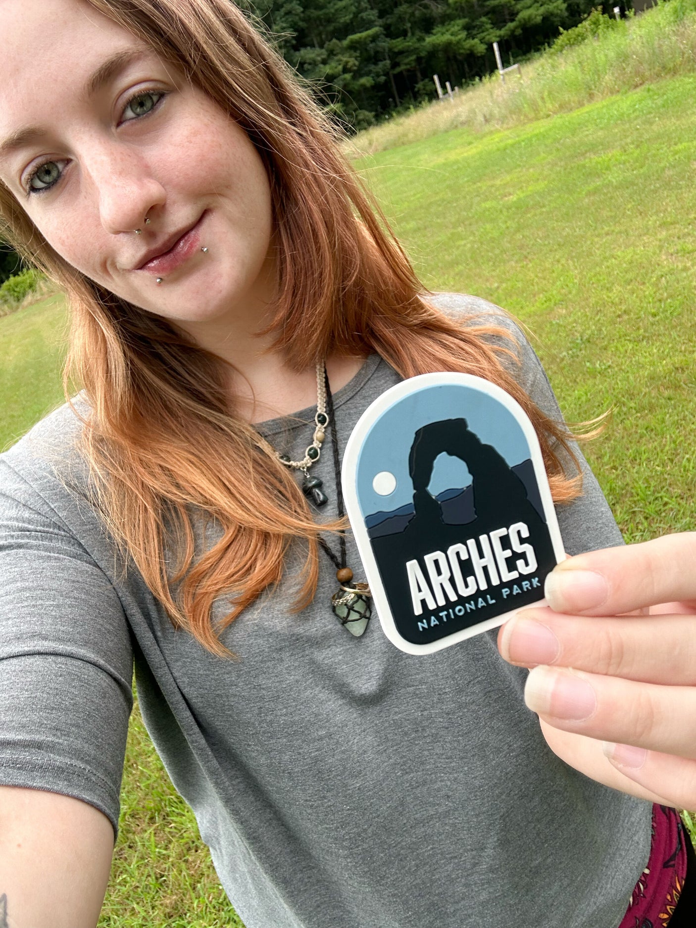 Arches National Park fridge magnet held by a person, featuring a silhouette of an arch against a blue background.