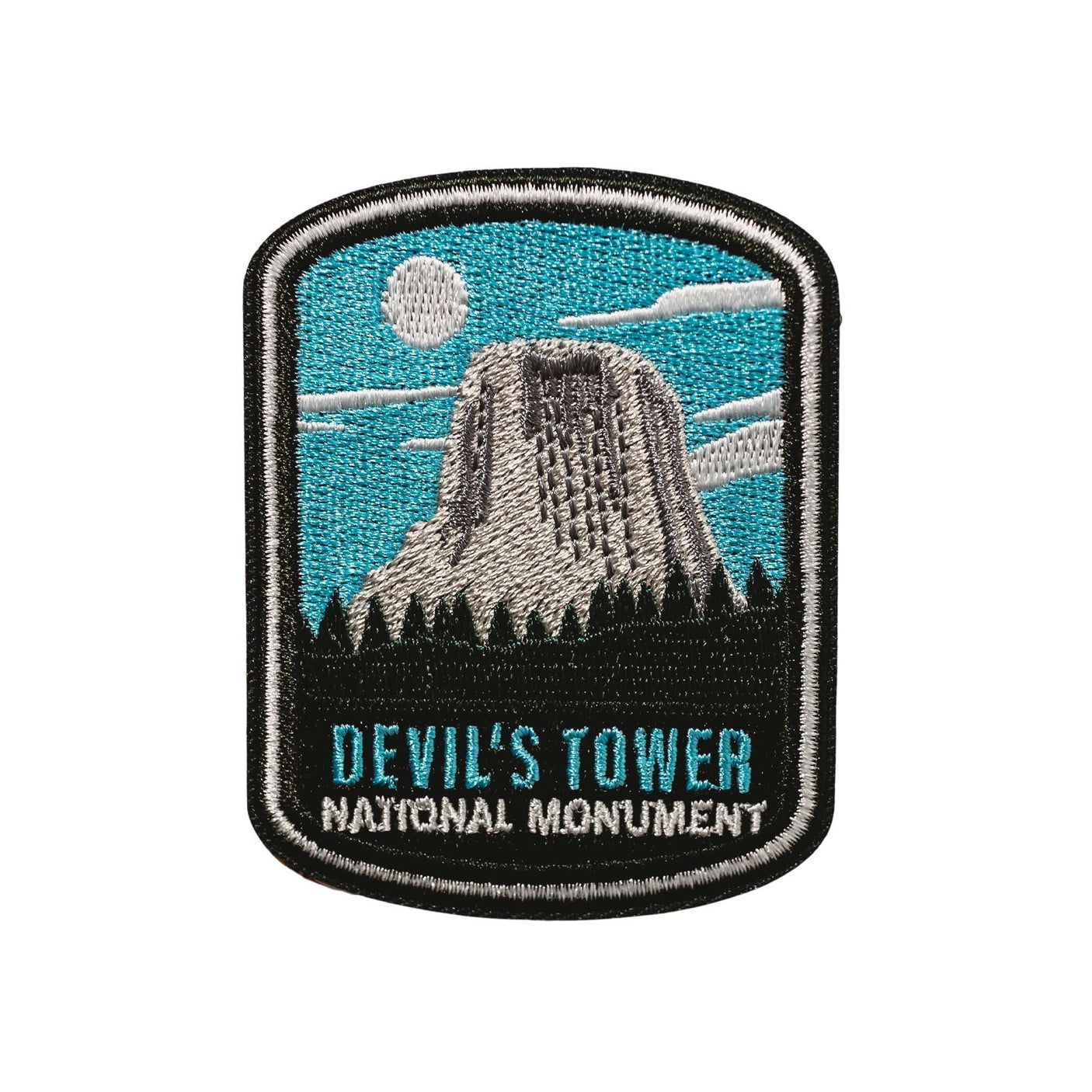 Devil’s Tower National Monument iron-on patch featuring a blue sky, clouds, and the iconic tower silhouette.
