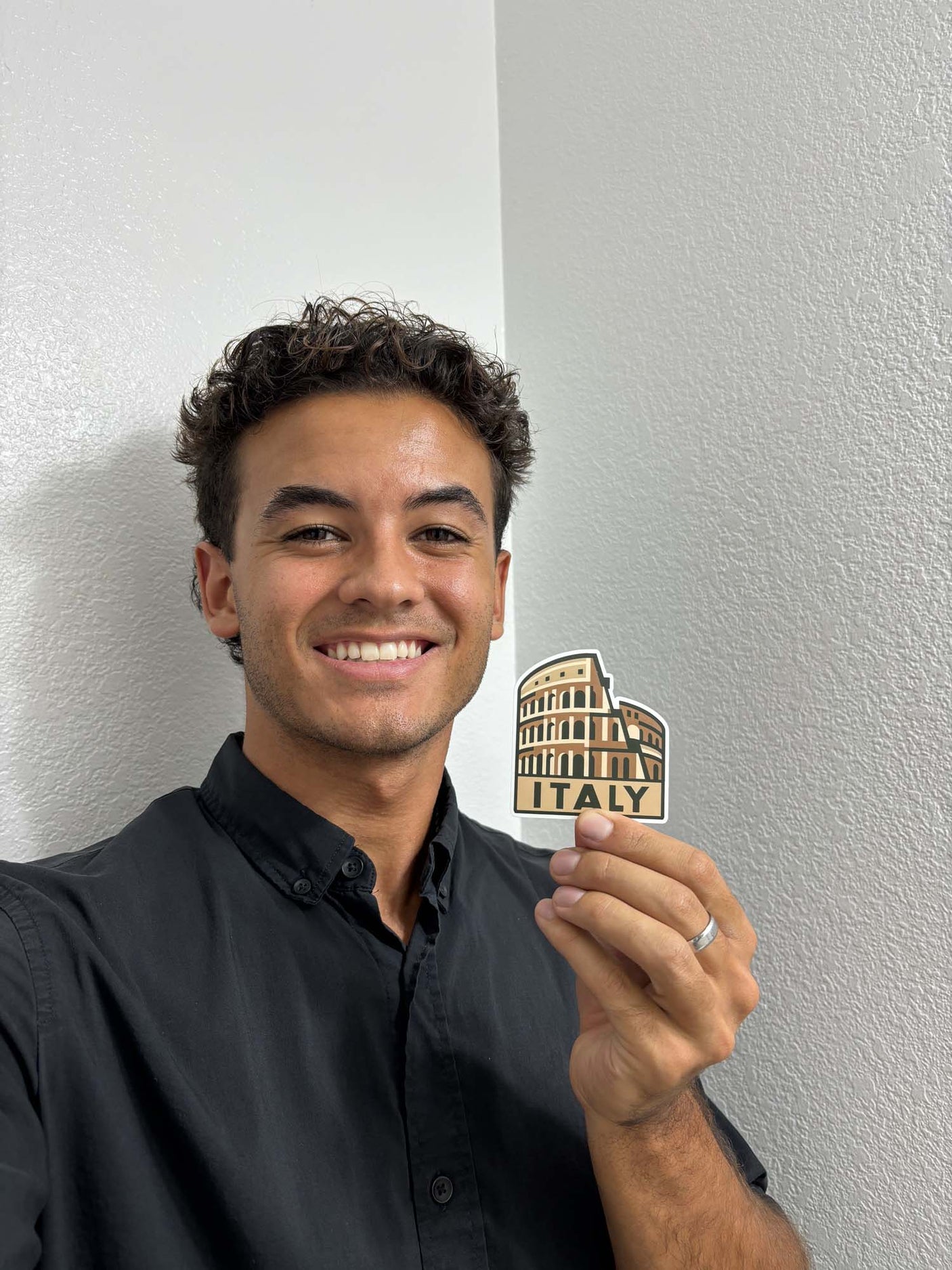 A person holding an Italy sticker featuring the Colosseum design with the word "ITALY" in bold letters.