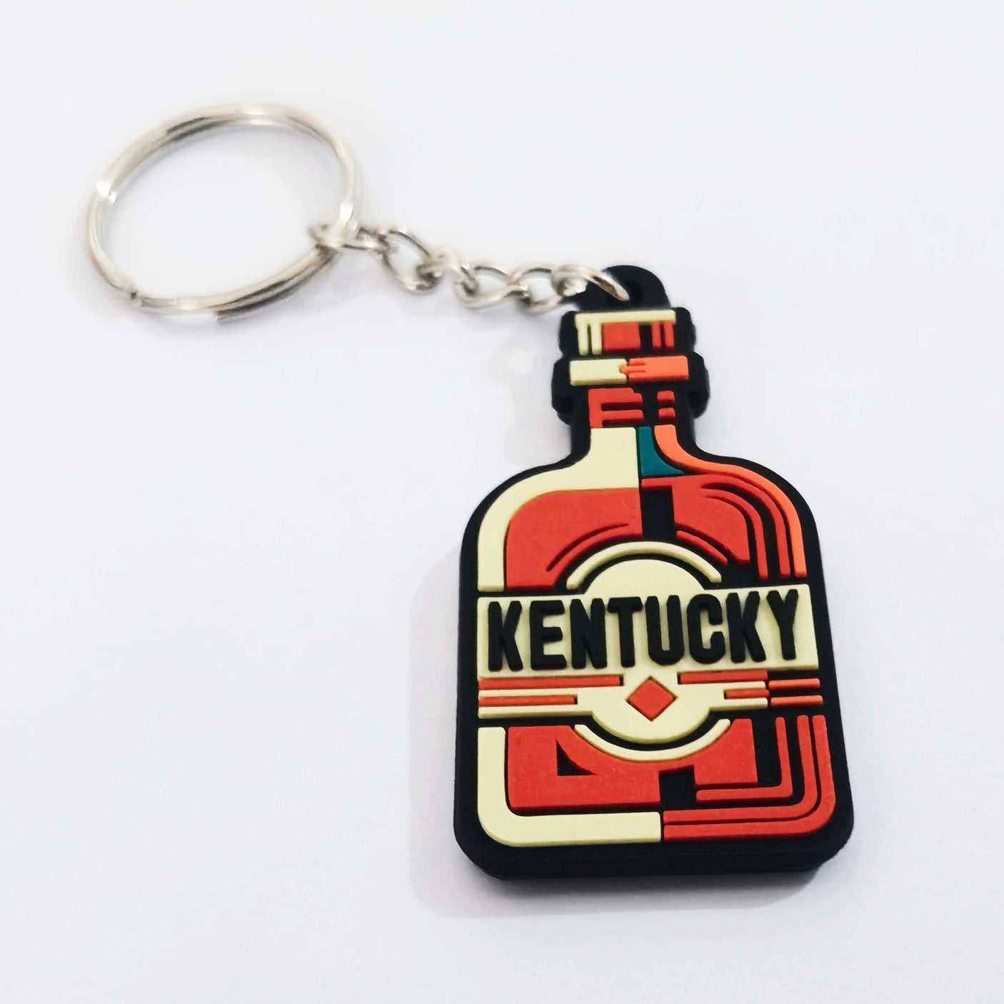 Kentucky keychain shaped like a whiskey bottle, featuring red, yellow, and black colors with bold lettering.