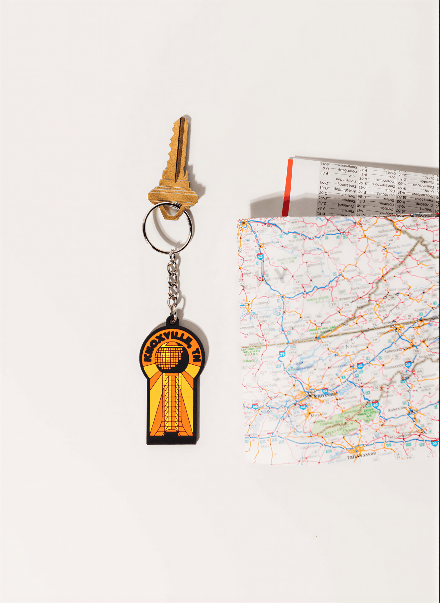 Memphis keychain featuring a yellow and black design with a tower graphic, next to a key and a map.