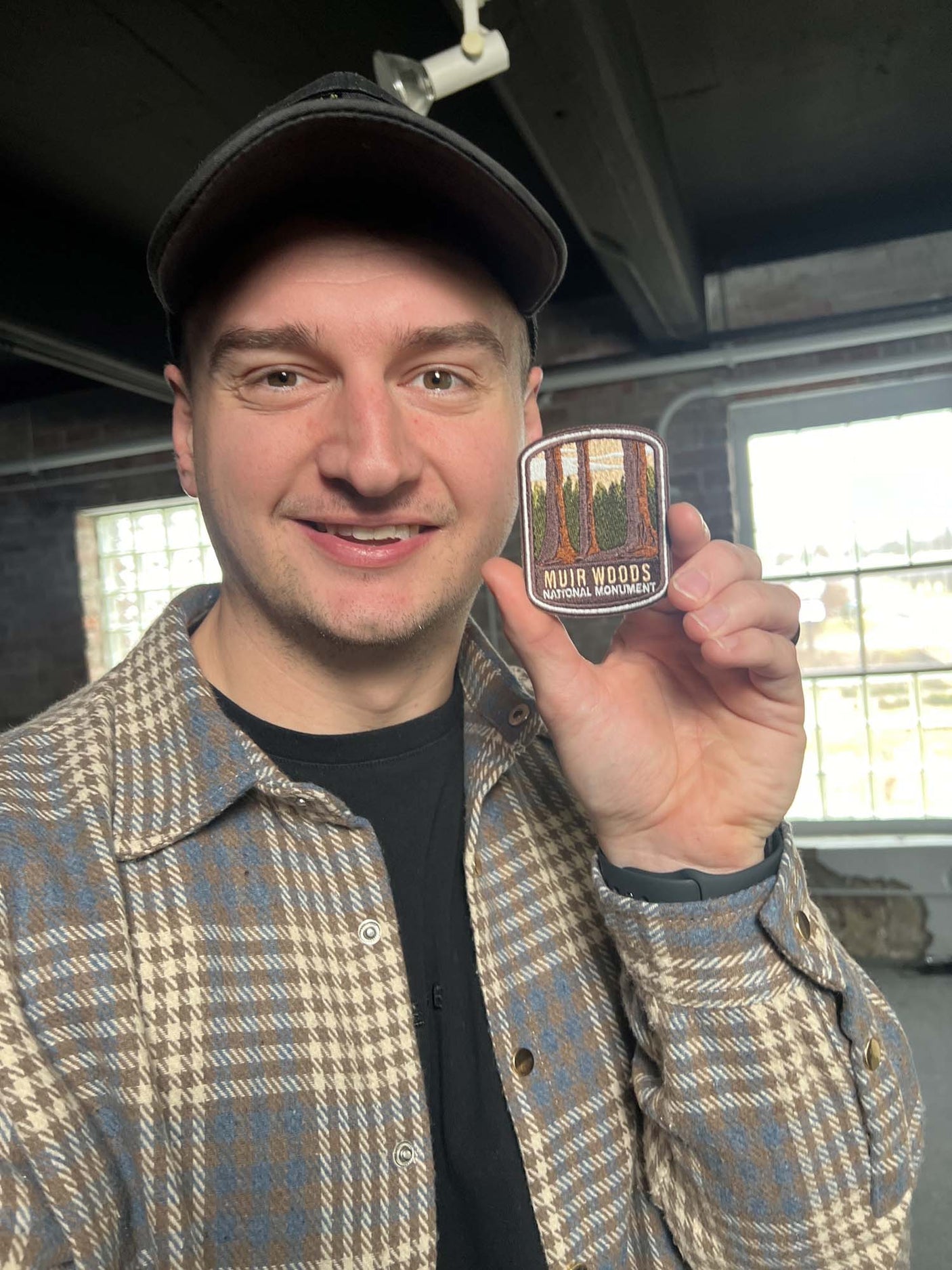 Muir Woods National Monument iron-on patch held by a person, featuring a tree design and earthy colors.