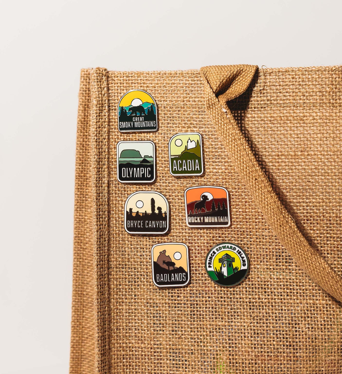 Key West Mile 0 enamel pin with sunset and palm trees, displayed on a burlap background alongside various other pins.