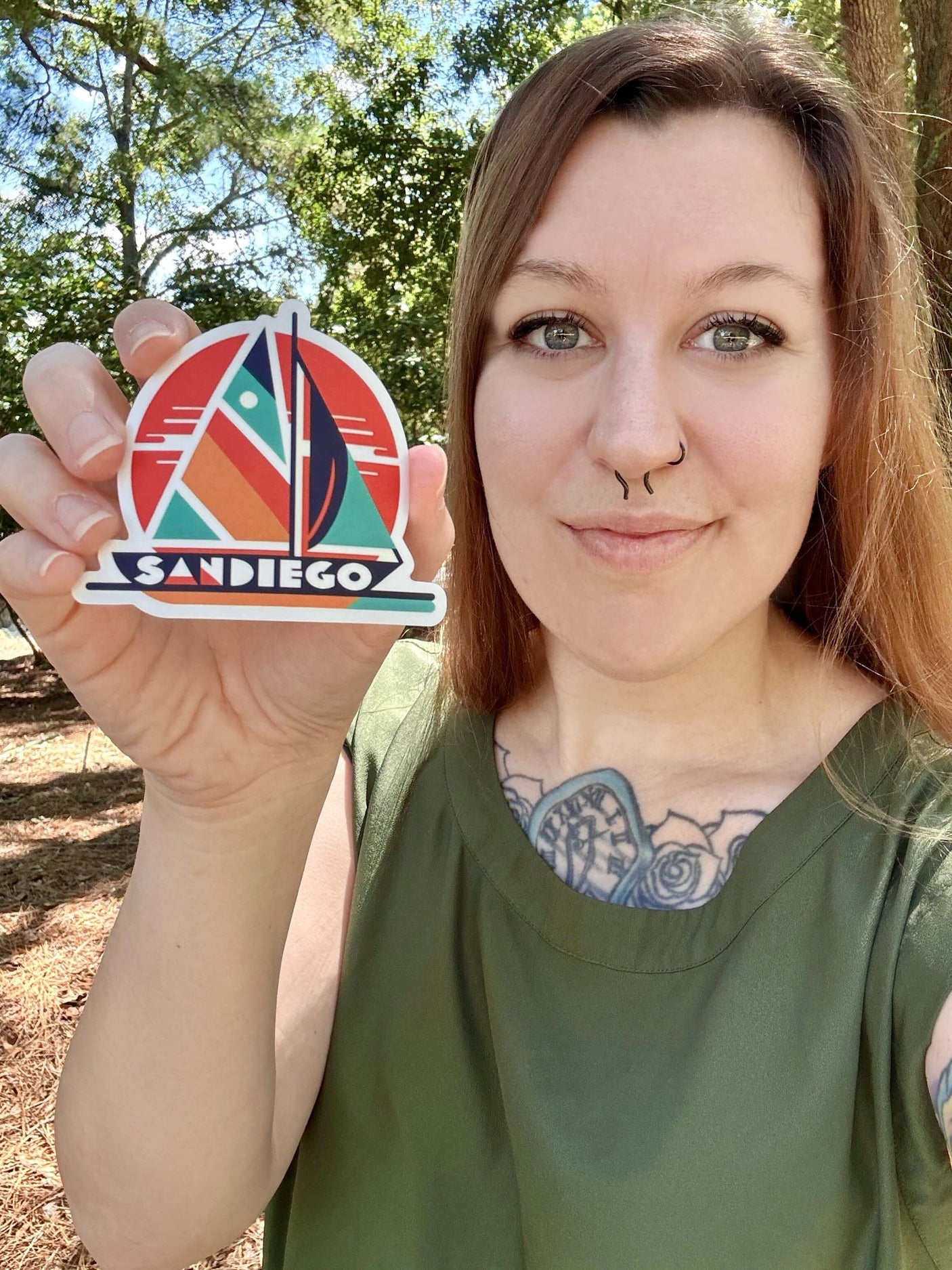 San Diego sticker held by a woman with a green top, featuring vibrant colors and geometric design elements.