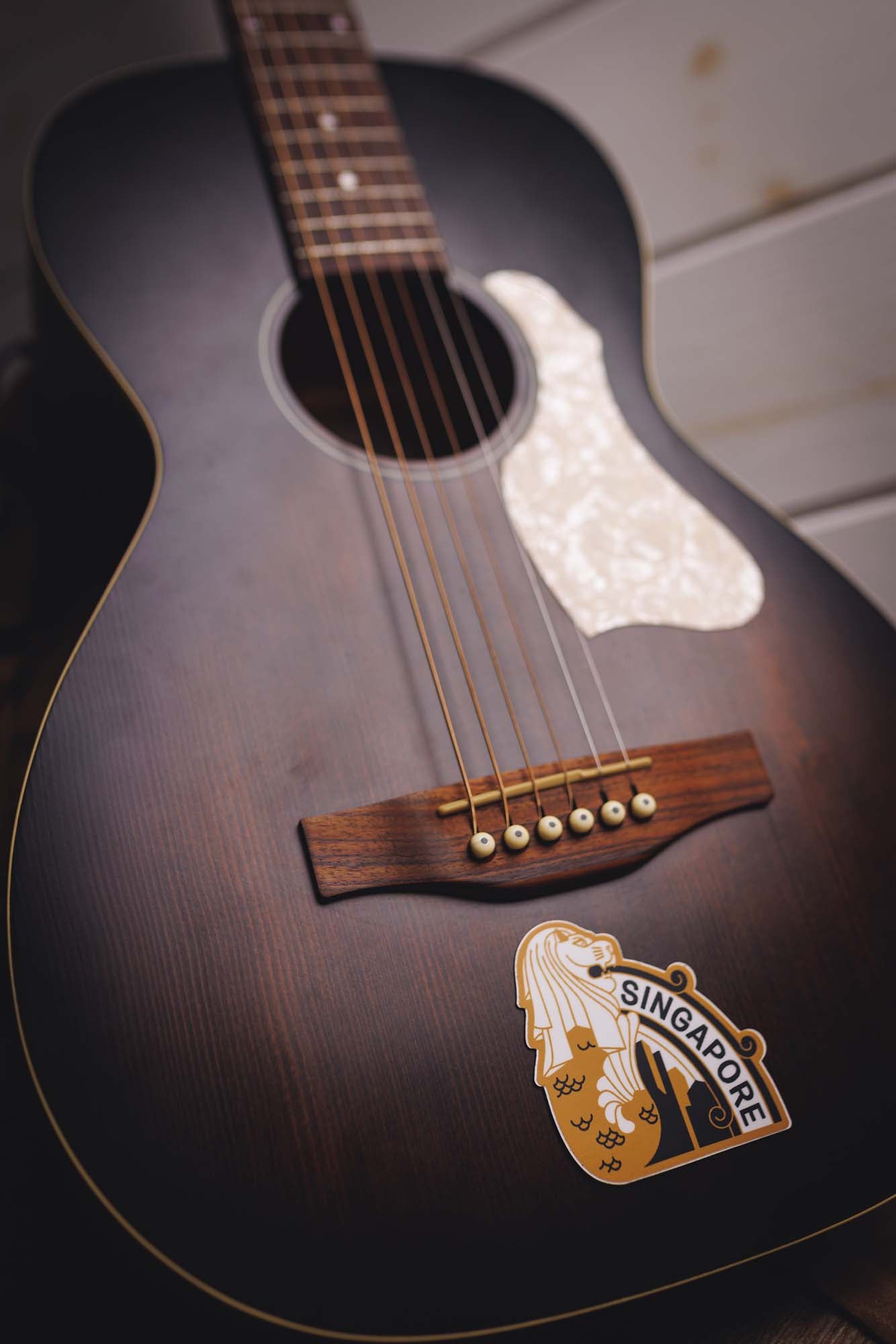 Governor’s Island National Monument vinyl sticker on a dark acoustic guitar with a wooden bridge and pearl inlay.