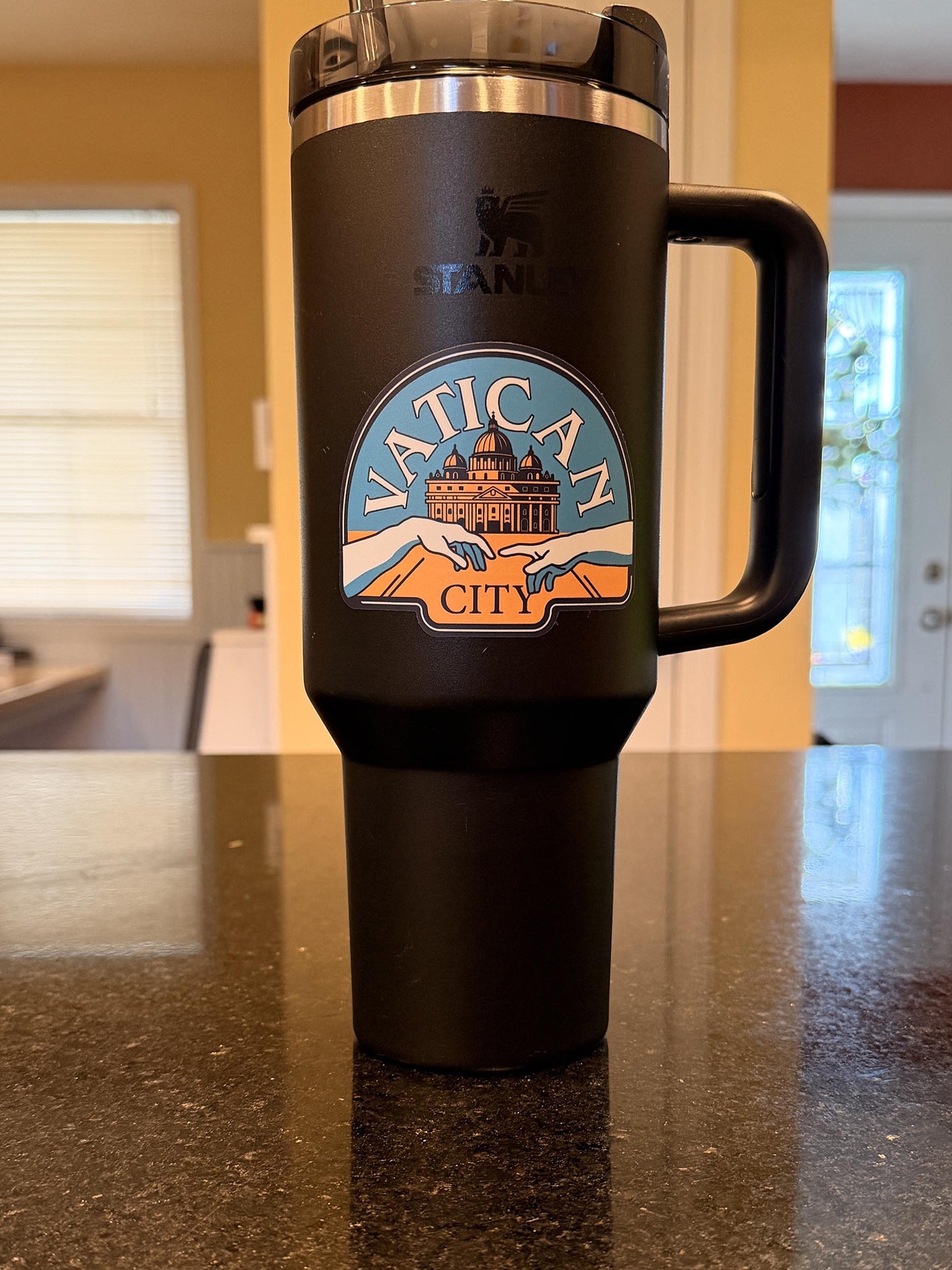 Vatican City sticker on a black travel mug, displayed on a dark kitchen counter.