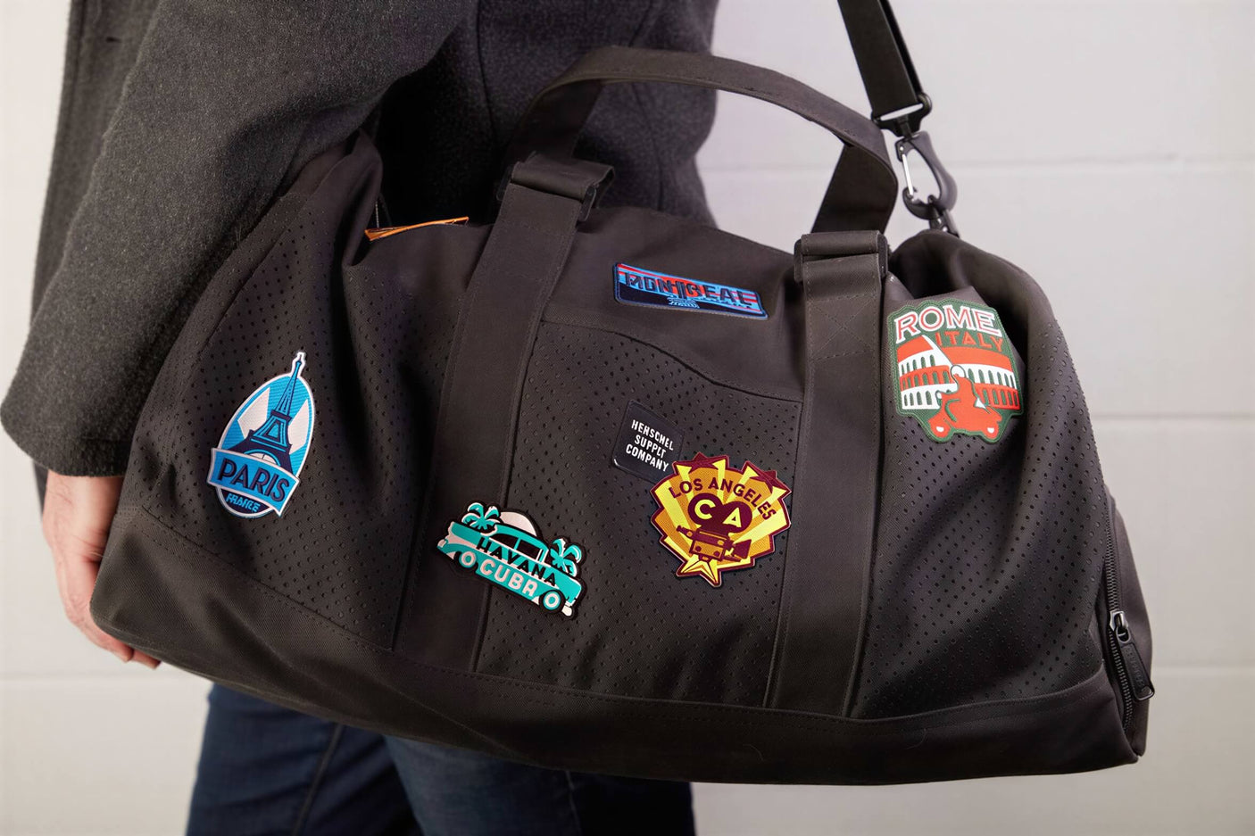 Muir Woods National Monument iron-on patch displayed on a black duffel bag with various travel-themed patches.