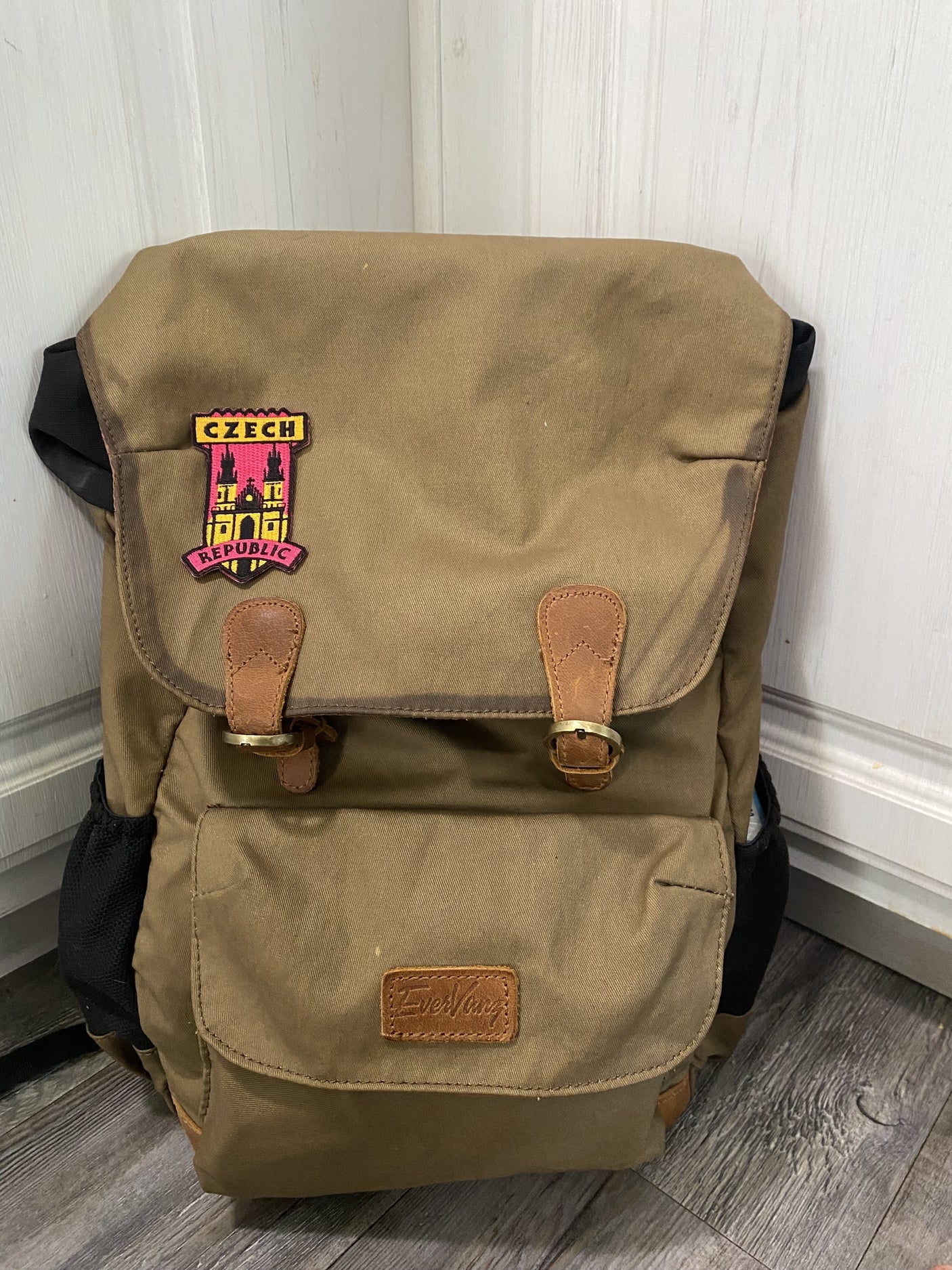Czech Republic patch with castle design sewn on a brown backpack featuring leather straps and side pockets.