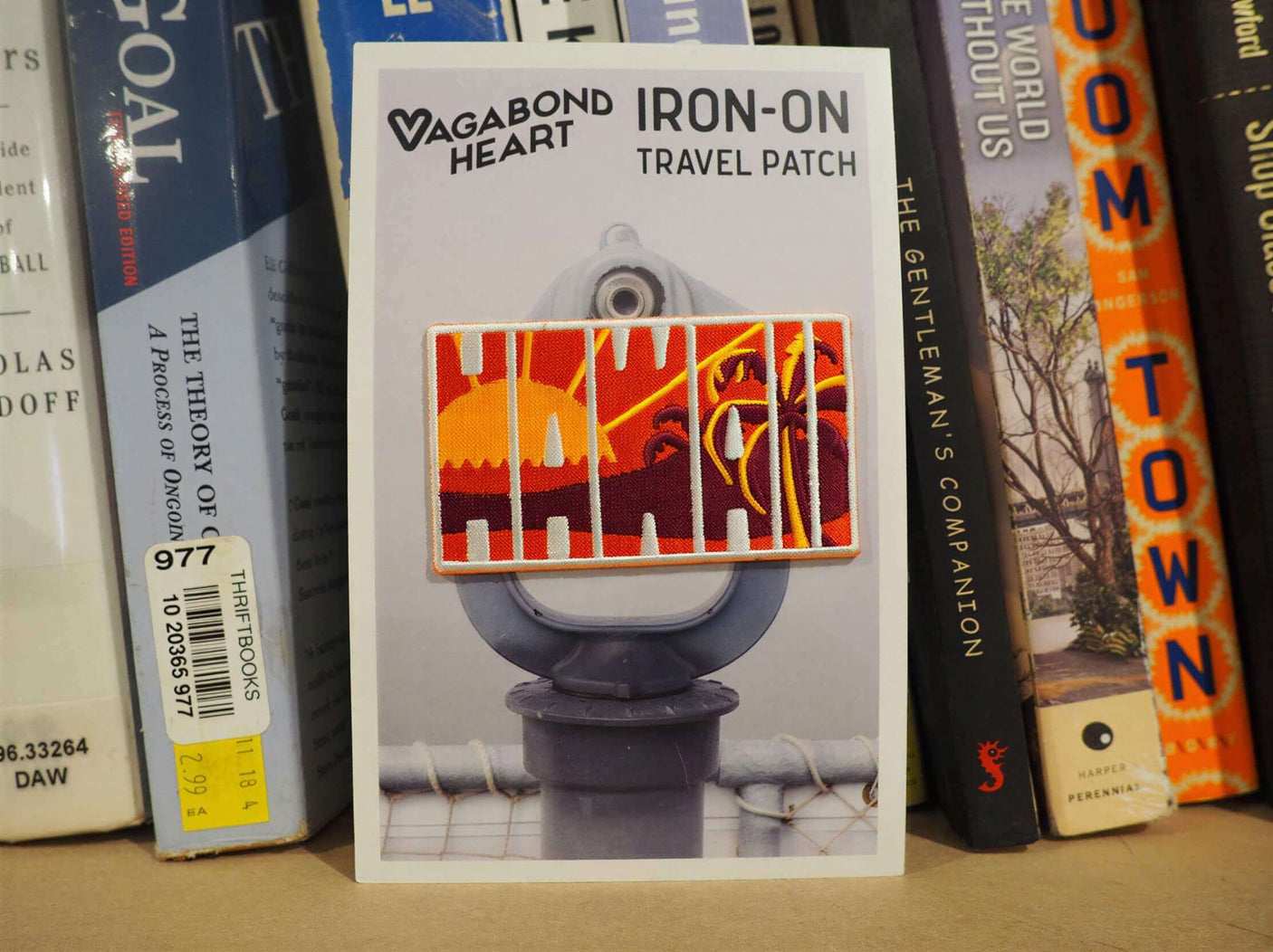 Hawaii patch featuring a sunset design on a backing card, displayed against a bookshelf background.