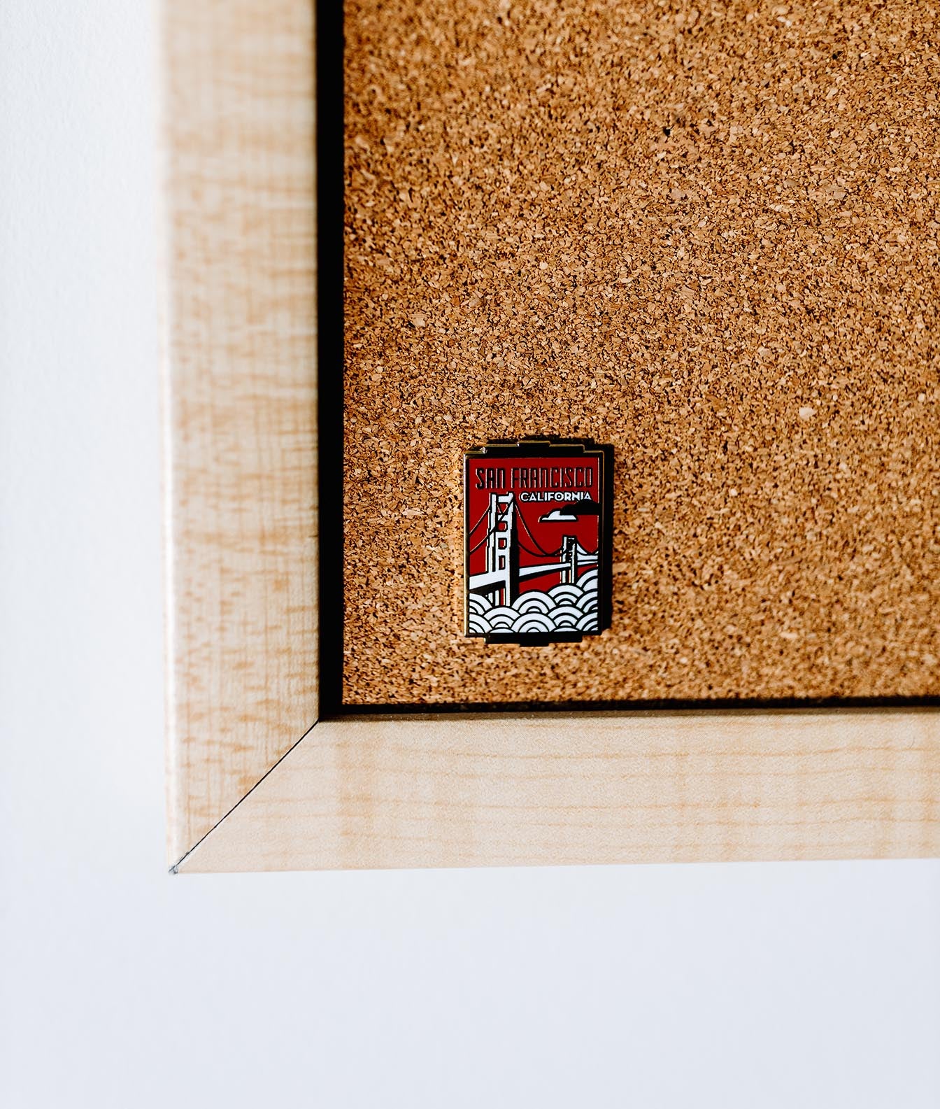 San Francisco California enamel pin featuring the Golden Gate Bridge design on a corkboard background.