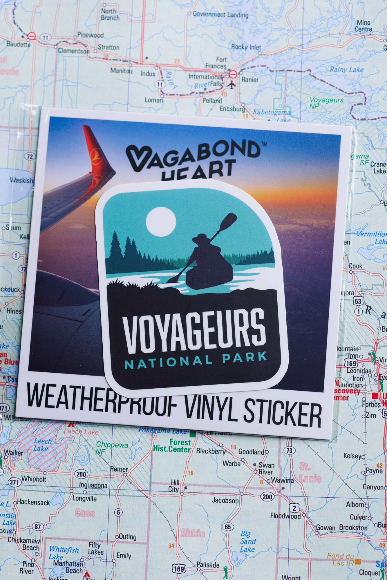 Voyageurs National Park sticker featuring a kayak silhouette against a teal background, mounted on a map.