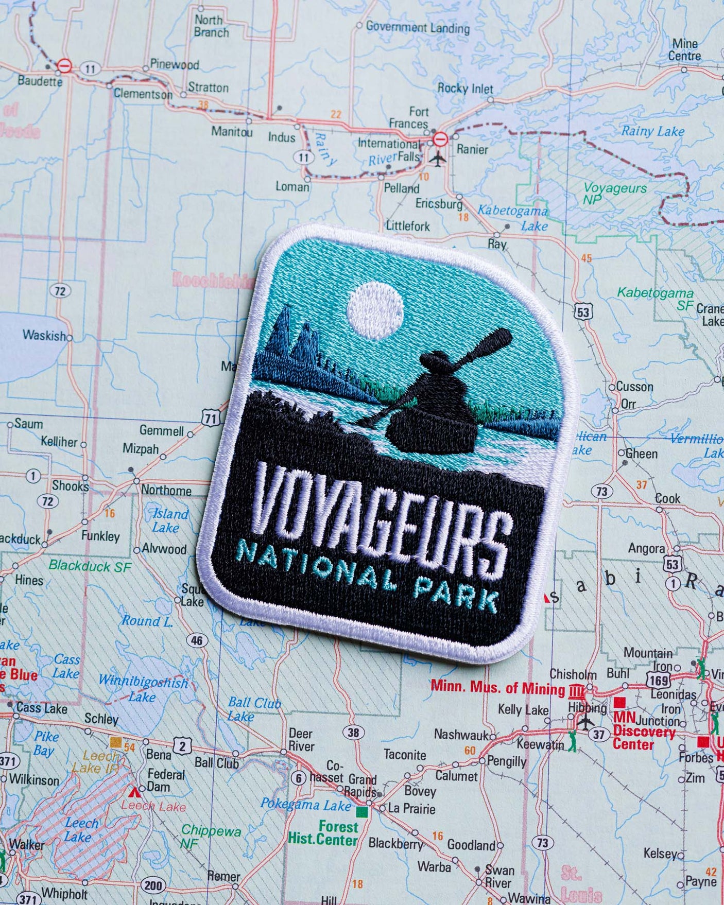 Voyageurs National Park patch featuring a canoeist, set against a map background with lakes and mountains.