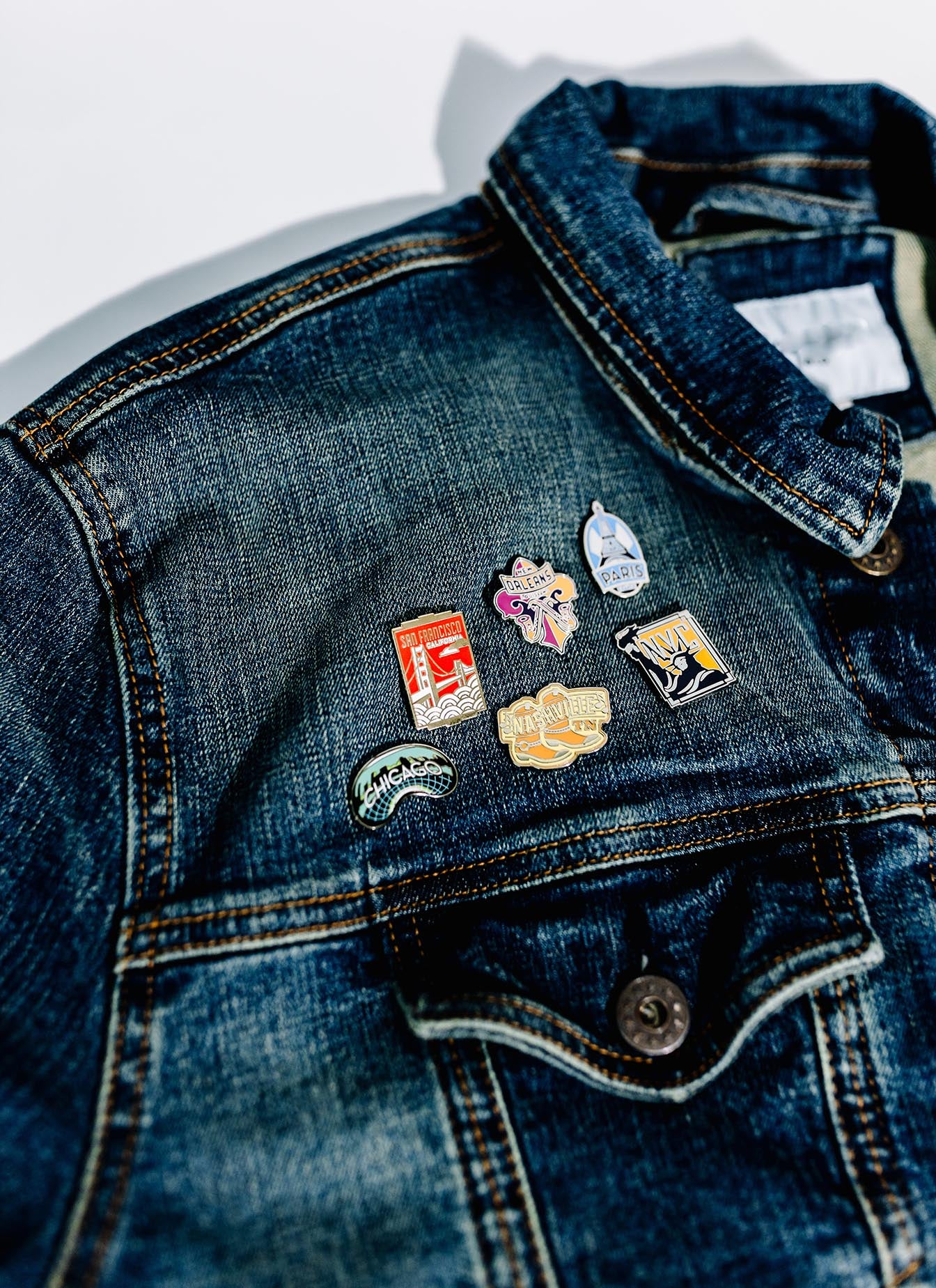 San Francisco California enamel pin displayed on a dark denim jacket, among other travel-themed pins.
