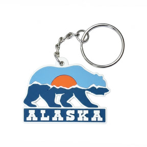 Alaska keychain featuring a bear silhouette with a sunset and mountain design in blue, orange, and white colors.