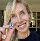 Greece enamel pin featuring a blue and white church design held by a smiling person.