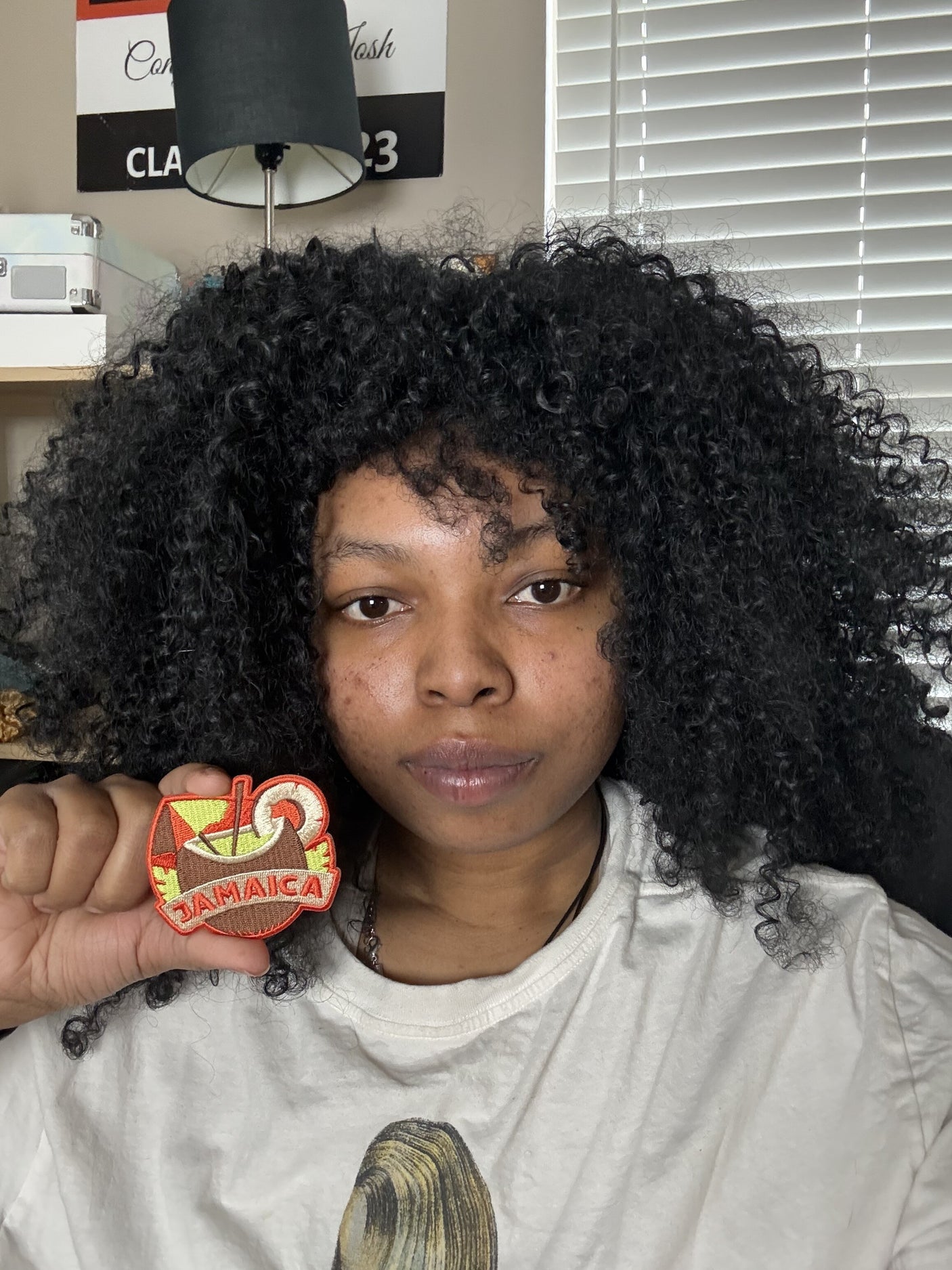 Jamaica patch held by a person with curly hair, featuring vibrant colors and a tropical design.