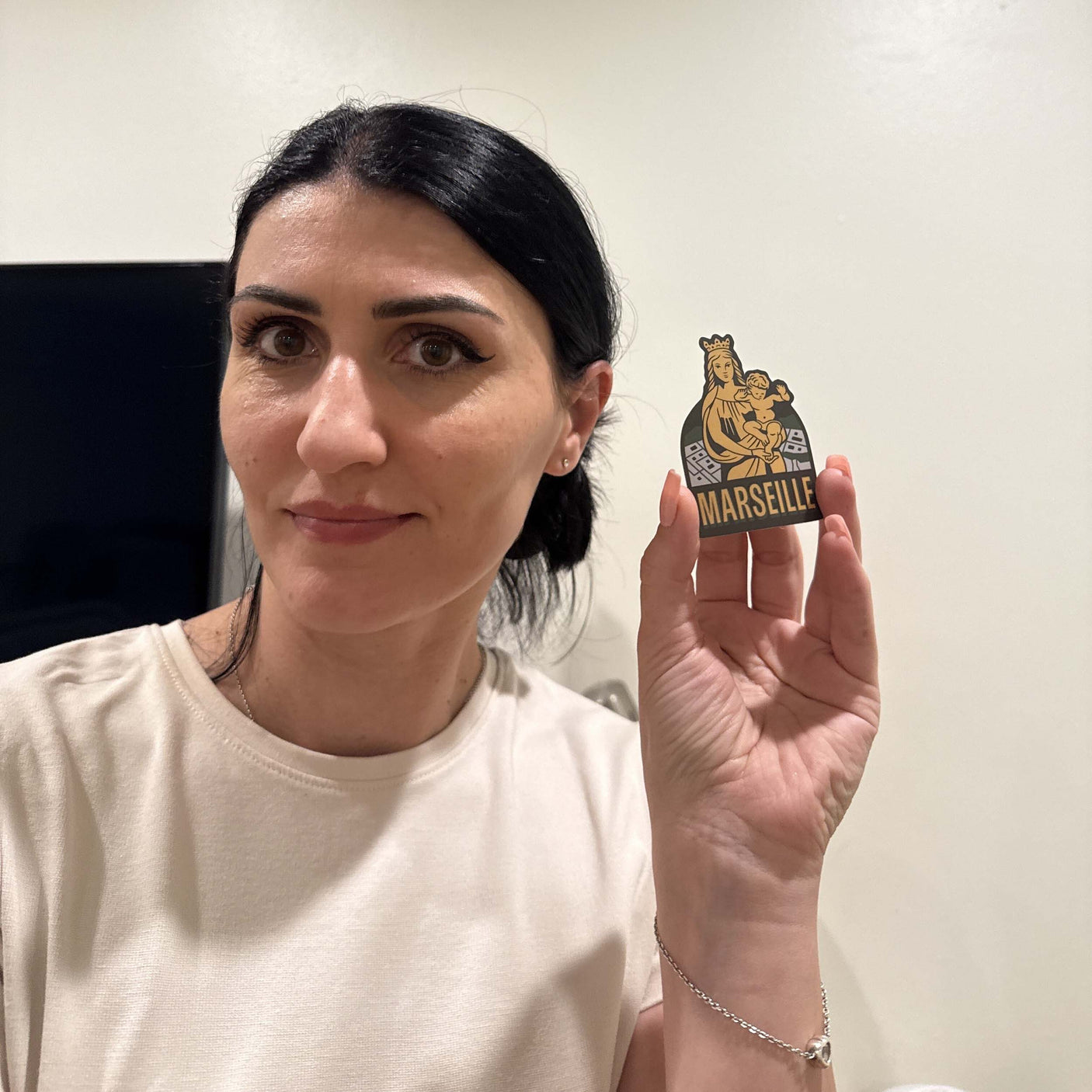 Woman holding a Marseille sticker featuring a lion emblem and the word "Marseille" in bold lettering.