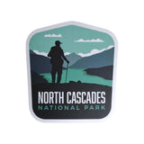North Cascades National Park sticker featuring a hiker silhouette against mountains and a river in green and blue tones.