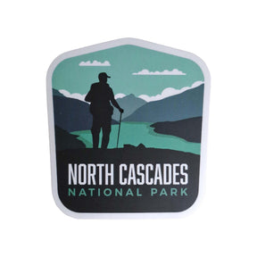 North Cascades National Park sticker featuring a hiker silhouette against mountains and a river in green and blue tones.
