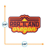 Portland Oregon sticker featuring bold orange and yellow text with mountain graphics, measuring 3.25 by 2.25 inches.