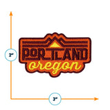 Portland Oregon patch featuring orange and yellow text with mountain graphics, measuring 2 inches by 3 inches.