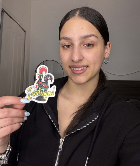Person holding a sticker with 'Portugal' text and rooster symbol.