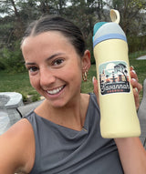 Woman smiling while holding a yellow water bottle featuring a Savannah, Georgia sticker with palm trees and buildings.