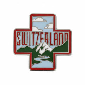 Switzerland enamel pin featuring a red cross design with mountains, clouds, and a river in green and blue colors.