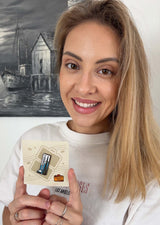 Toronto enamel pin displayed on a beige backing, held by a woman with long blonde hair, smiling.