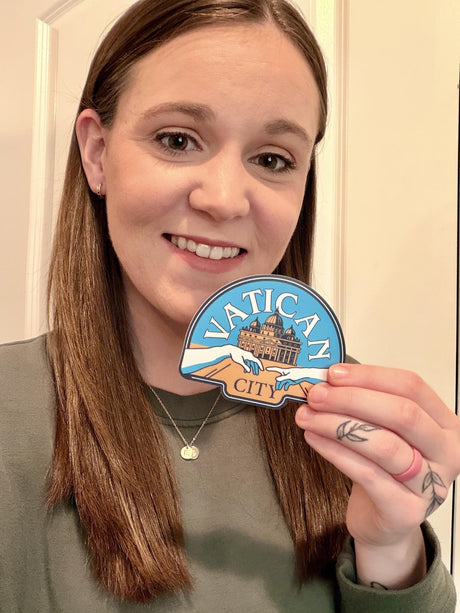 Person holding a Vatican City sticker in front of a neutral background