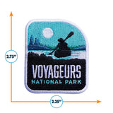 Voyageurs National Park patch featuring a canoe silhouette, mountains, and a sunlit sky, measuring 2.75 by 2.25 inches.