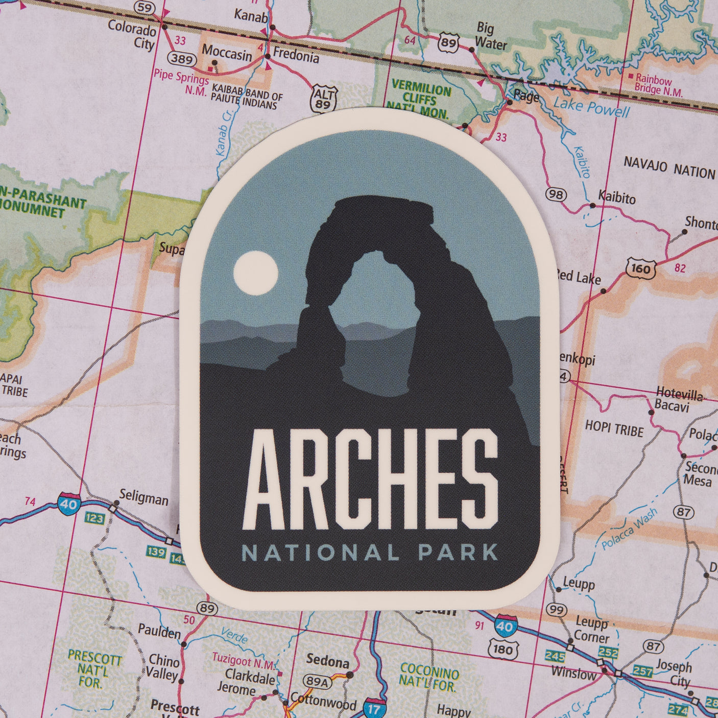 Arches National Park sticker featuring the iconic rock formation and a moon against a map background.