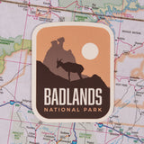 BONUS National Park sticker featuring a silhouette of a goat against a sunset background with "Badlands National Park" text.