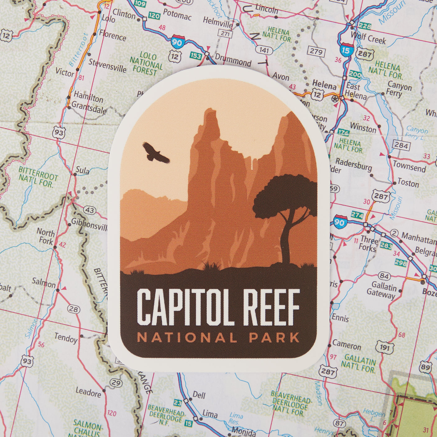 Capitol Reef National Park sticker featuring red rock formations and a silhouette of a tree on a map background.