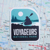 Voyageurs sticker on a map background